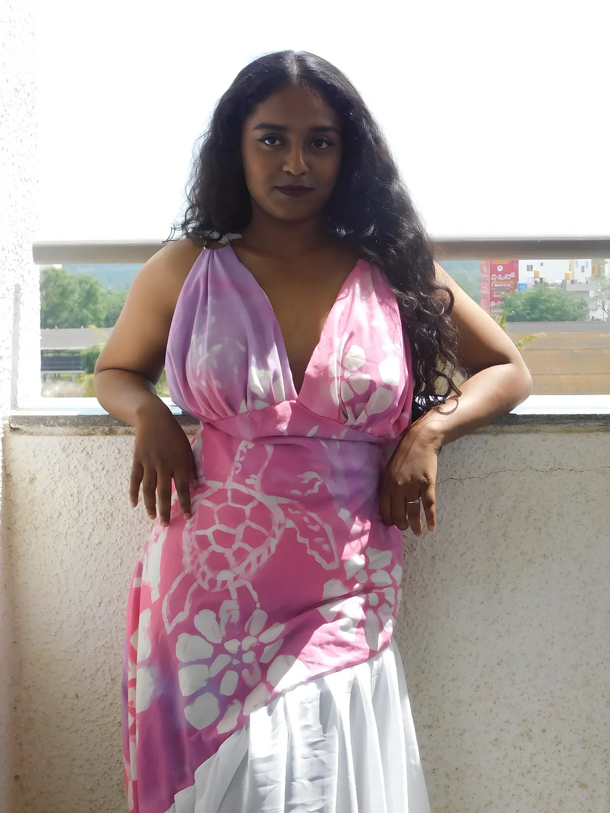 Madhumitha in the batik gown by a window